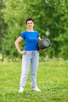 Portret of Senior Woman Exercising In Park. Elderly female doing fitness exercises outdoor. Heathy life style concept. Copyspace. photo