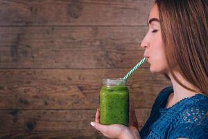 Woman holding kiwi smoothie. Healthy lifestyle concept. Dark wooden background. photo