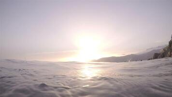 Coast line with people bathing at sunset with a camera submerged in the sea video