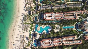 aéreo ver gastos generales perspectiva de línea costera durante atardecer, exhibiendo claro turquesa aguas lapeado a playa. recurso complejo con hoteles líneas costa, ideal viaje destino para verano vacaciones. video