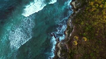 Beautiful cave rocky beach with blue water on sunrise in tropics. Aerial Drone video