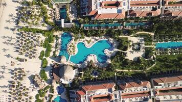 aereo superiore Visualizza di tropicale ricorrere con nuoto piscina la zona, famiglia divertimento nel vacanza, tutti compreso viaggio e tempo libero. di fronte all'oceano e spiaggia gli ombrelli. tramonto. segreti reale spiaggia. Ingrandisci fuori. video