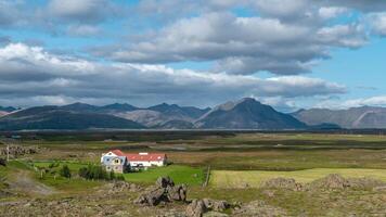 Clouds move over the mountains in Iceland. Farm on the plain. Time lapse. video