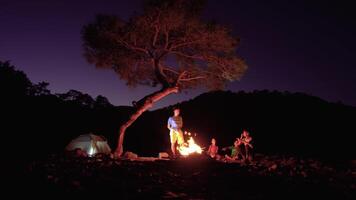 Tourist Familie in der Nähe von das Lagerfeuer beim Nacht. Freiheit und Reise Konzept. 4k video