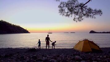 Father and sons on the shores of the Mediterranean Sea early in the morning. Concept of a happy family and travel. 4K video