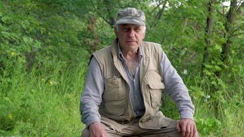 retrato de de edad mediana hombre. el antiguo hombre es sonriente y contento. en el antecedentes de verde bosque. video