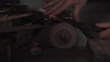 Hands of man sharpen blade of a knife on a sanding machine. Close up 4K video