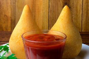 Coxinha in the dish, traditional Brazilian cuisine snacks stuffed with chicken, on rustic wooden table photo