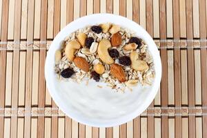 natural yogurt with homemade granola and nuts in ceramic bowl on a table top view photo