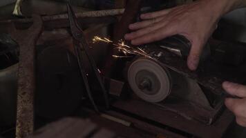 Hands of man sharpen blade of a knife on a sanding machine. Close up 4K video