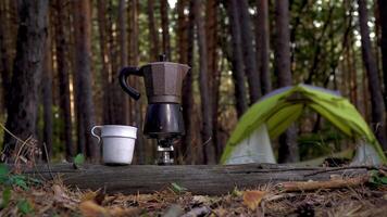 Aromatic coffee is prepared in a geyser coffee maker. Green tent in the forest in the background. Travel and healthy lifestyle concept video