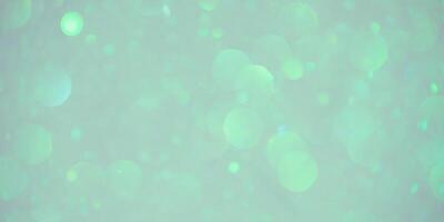 Beige background with green and blue defocus lights. Abstract glitter background. Bokeh photo