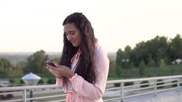 A beautiful girl walks down the street and uses a smartphone. slow motion. video