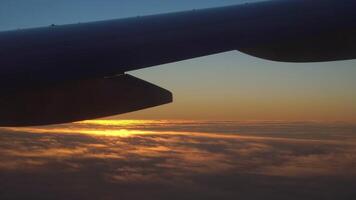 View from the airplane window of the wing, clouds and a beautiful sunset. video