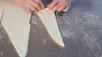 Female hands twist a piece of dough into a triangle to make a baguette. Close-up of female hands twisting bagels. photo