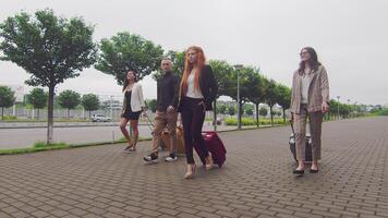 grupo de turistas caminando con equipaje en el antecedentes de el aeropuerto Terminal. un grupo de joven empresarios con equipaje voló a un nuevo ciudad y caminar en contra el fondo de un nuevo moderno aeropuerto foto