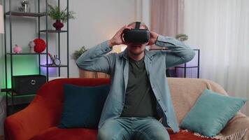 Adult man use virtual reality headset glasses at home, enjoying video concept moving hands in air