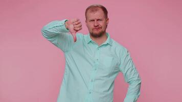 Upset man in casual shirt showing thumbs down sign gesture, disapproval, dissatisfied dislike video