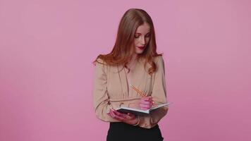 Pensive businesswoman making notes writing down thoughts with pen into notepad notebook diary indoor video