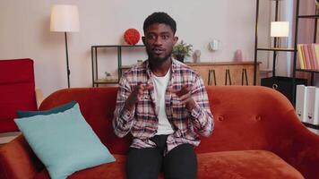 Man sitting on home sofa, looking at camera, making video conference call with friends or parents