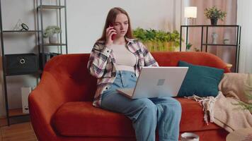 Young woman using laptop computer sitting on sofa working, online shopping from home office video