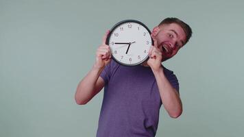 Young man holding clock watch, hiding, checking time on clock, running late to work being in delay video