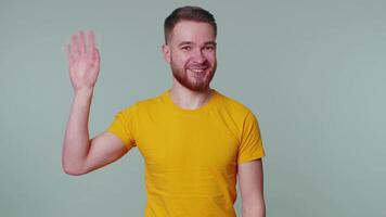 Bearded man smiling friendly at camera and waving hands gesturing hello or goodbye, welcoming video