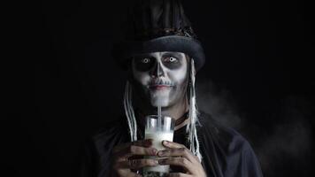 Siniestro hombre con esqueleto maquillaje en sombrero de copa. chico mirando a cámara, bebidas Leche desde un vaso video