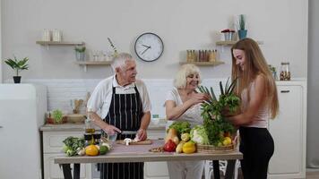 äldre par i kök tar emot grönsaker från barnbarn. rå mat friska äter diet video