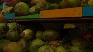 Person standing next to a tropical fruit stand with fresh coconuts on display. video