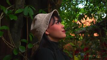 profil de une souriant Jeune femme portant une chapeau, avec une flou Naturel Contexte. video