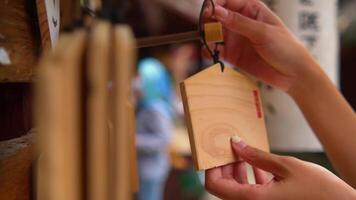 Close-up of a hand ringing a traditional Shinto shrine bell in Japan, with blurred background. video