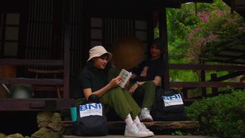 Two friends enjoying a relaxed conversation on a porch with a lush garden background. video