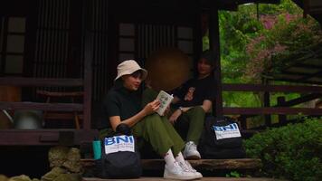 Two friends enjoying a relaxed conversation on a porch with a lush garden background. video