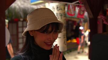 Smiling woman with hat at a festival stall, blurred background with festive decorations. video