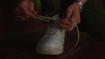 Close-up of hands tying shoelace on a white sneaker. video