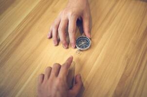 Hands on a wooden surface guiding a compass, symbolizing direction, exploration, and navigation photo