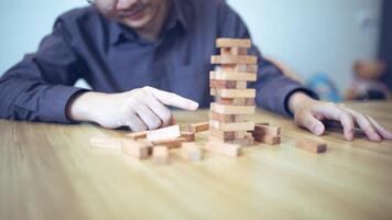Business strategy concept with hands playing a wooden block tower game, symbolizing risk and stability. Planning risk management photo