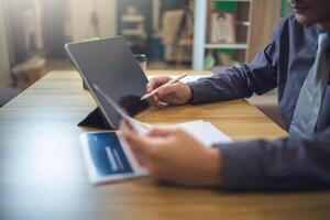 Businessman analyzing bar graph data with pen in hand, laptop and coffee on desk. Business concept photo