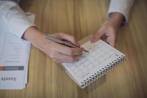 profesional ajuste un calendario en un planificador con un bolígrafo, en medio de un centrado en los negocios espacio de trabajo foto