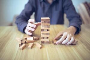 Business strategy concept with hands playing a wooden block tower game, symbolizing risk and stability. Planning risk management photo