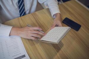 Professional setting a schedule in a planner with a pen, amidst a business-focused workspace photo