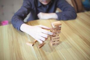 Business strategy concept with hands playing a wooden block tower game, symbolizing risk and stability. Planning risk management photo