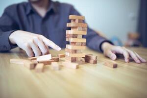 Business strategy concept with hands playing a wooden block tower game, symbolizing risk and stability. Planning risk management photo