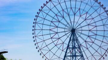 ein Zeitraffer von ziehen um Ferris Rad beim das Park hinter das Blau Himmel Zoomen video