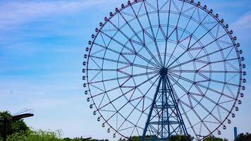 A timelapse of moving ferris wheel at the park behind the blue sky zoom video