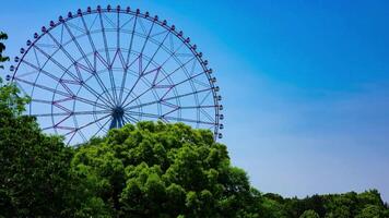 A timelapse of moving ferris wheel at the park behind the blue sky zoom video