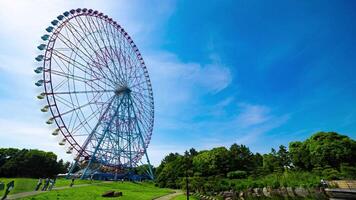 A timelapse of moving ferris wheel at the park behind the blue sky wide shot video