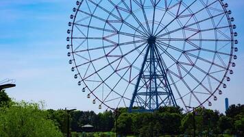 A timelapse of moving ferris wheel at the park behind the blue sky panning video