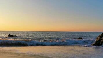 colorida dourado pôr do sol grande ondas pedras de praia porto escondido México. video